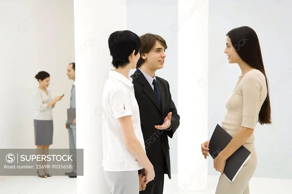 Young businessman introducing two business women to each other, smiling at each other