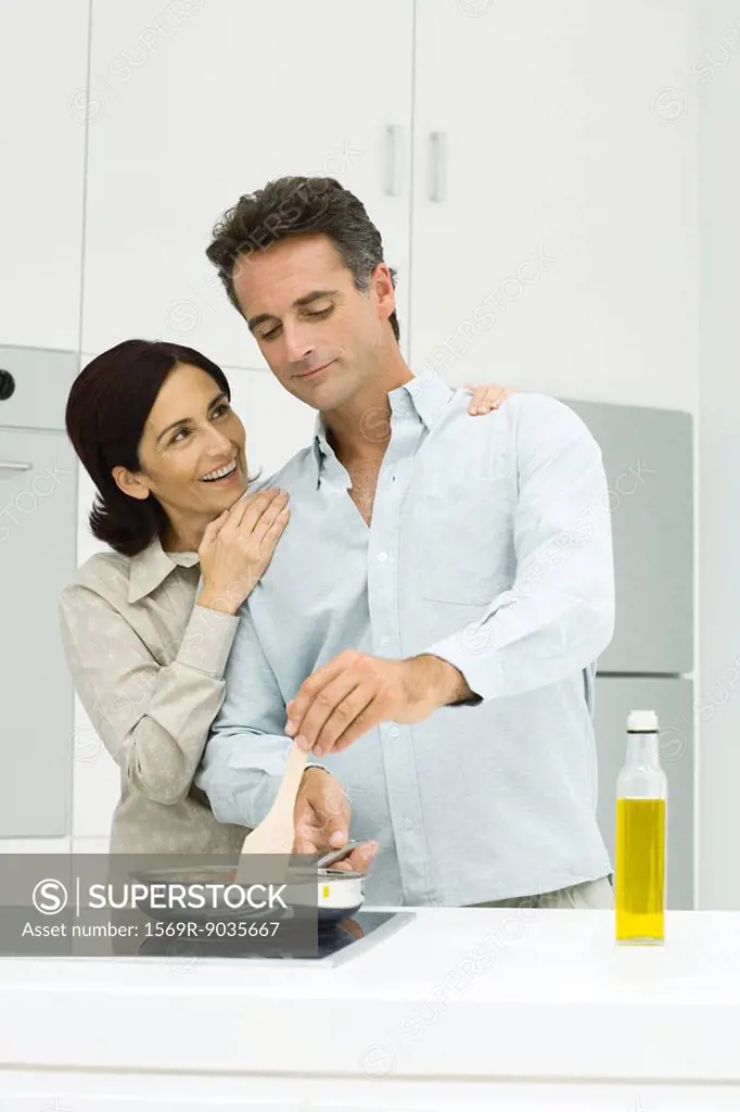 Couple cooking together in kitchen, woman putting hands on man´s shoulders