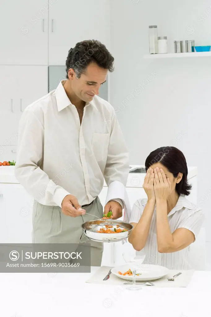 Husband serving wife surprise meal, woman covering eyes with hands