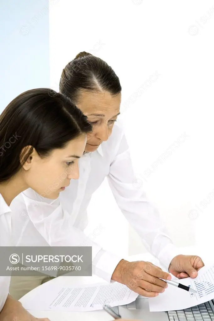 Senior woman in office, discussing document with younger colleague
