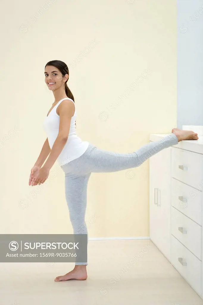 Woman stretching, leg up, smiling at camera