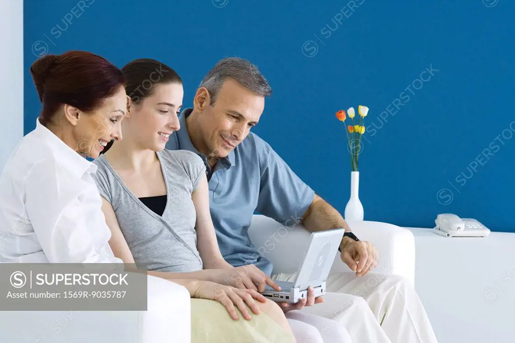 Family watching portable DVD player together on sofa