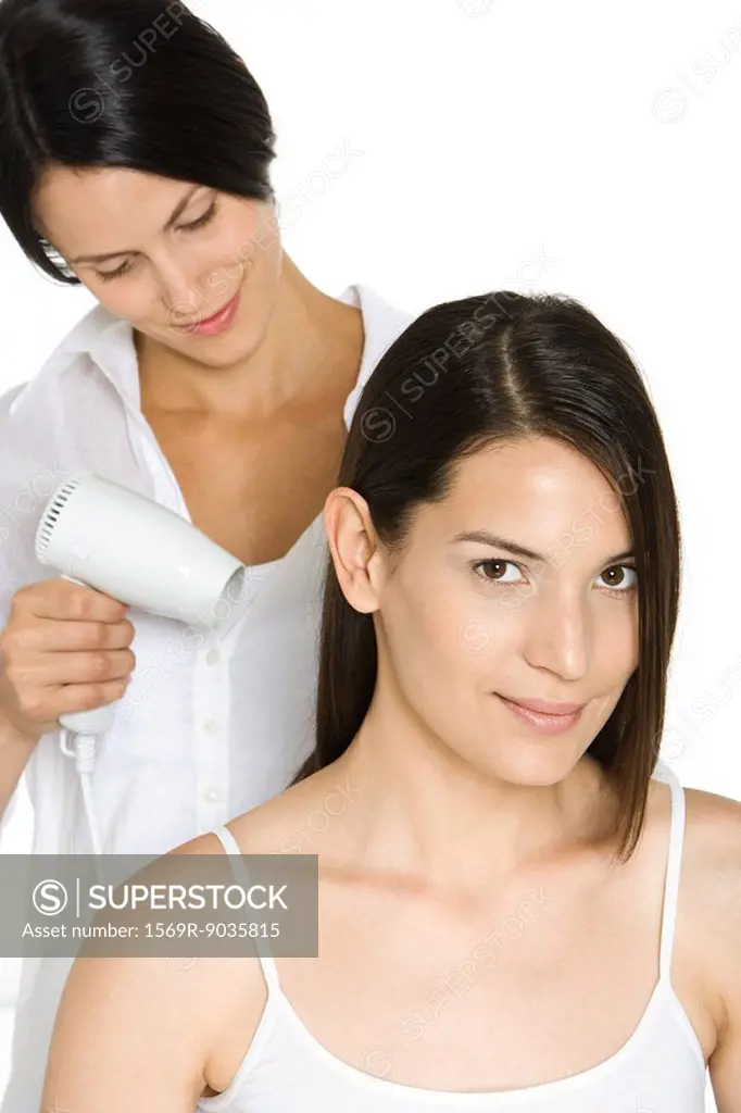 Woman having hair dried by stylist, smiling at camera