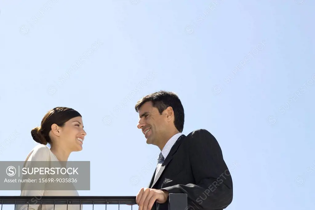 Business associates standing outdoors, smiling at each other, low angle view