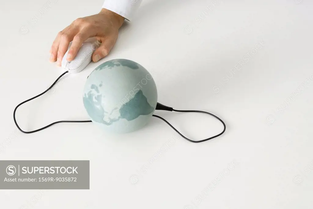 Hand using computer mouse connected to globe
