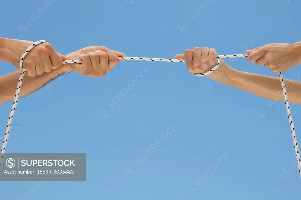 Hands playing tug-of-war with rope