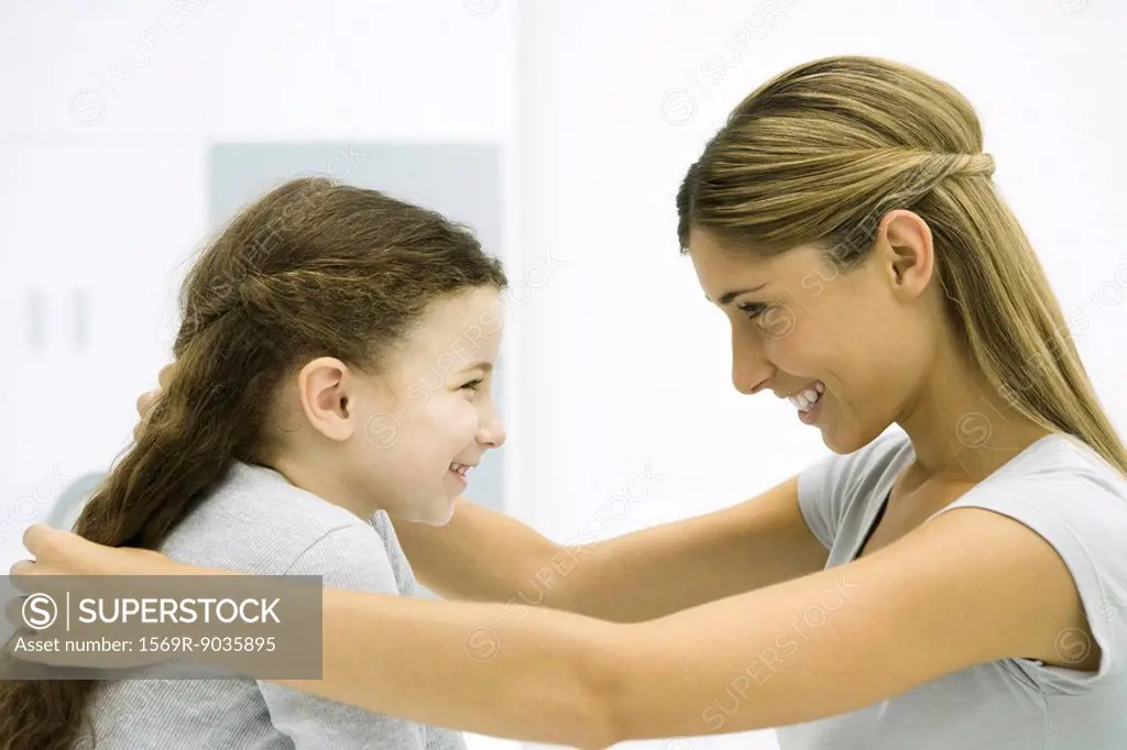 Mother and daughter face to face, smiling, woman touching girl´s hair