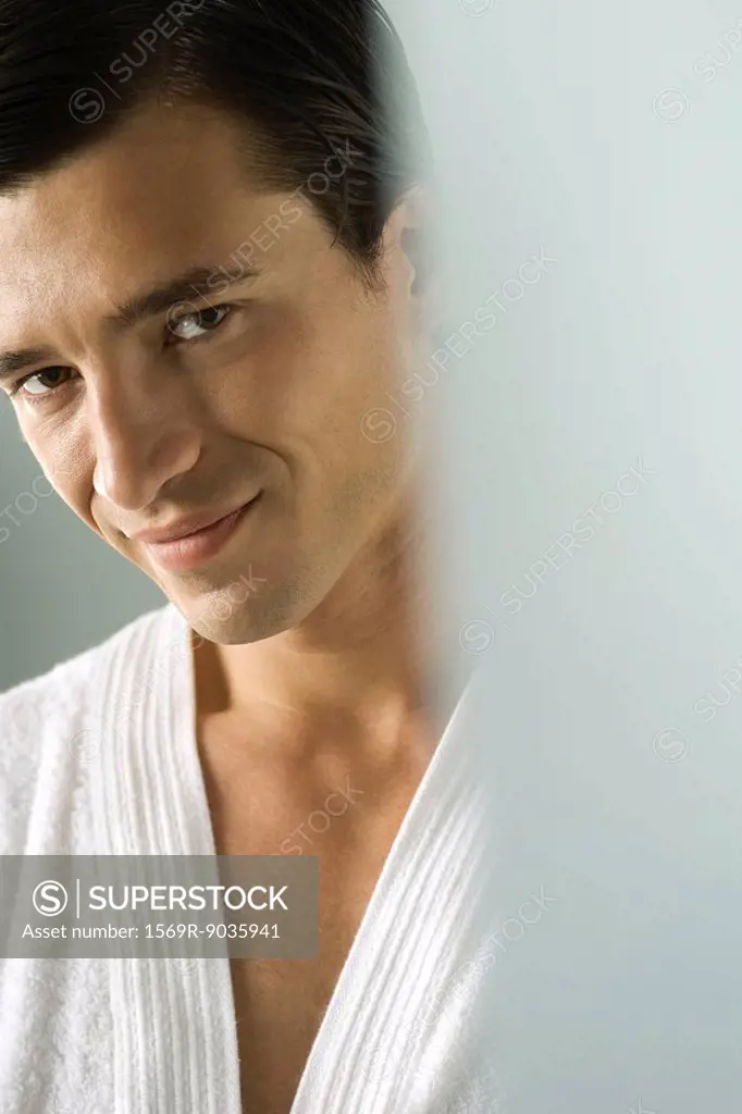 Man in bathrobe smiling at camera, portrait, cropped