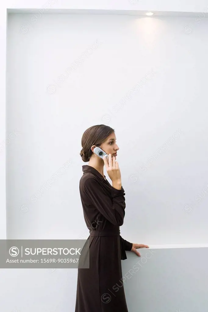 Well-dressed young female using cell phone, standing, side view