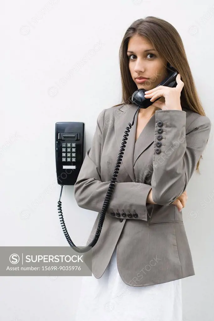 Teen girl using landline phone, looking at camera