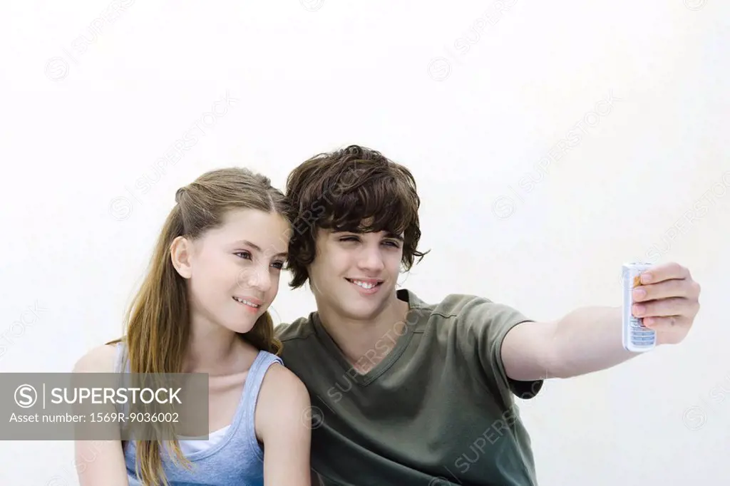 Teenage boy photographing himself and sister with camera phone
