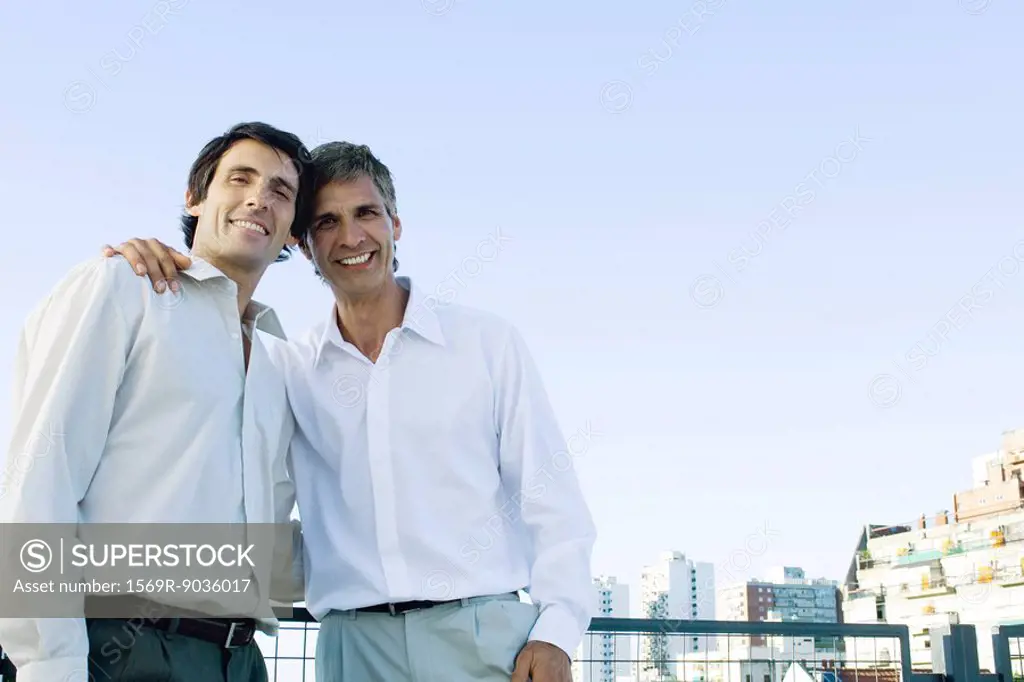 Man with his arm around another man, smiling at camera, portrait