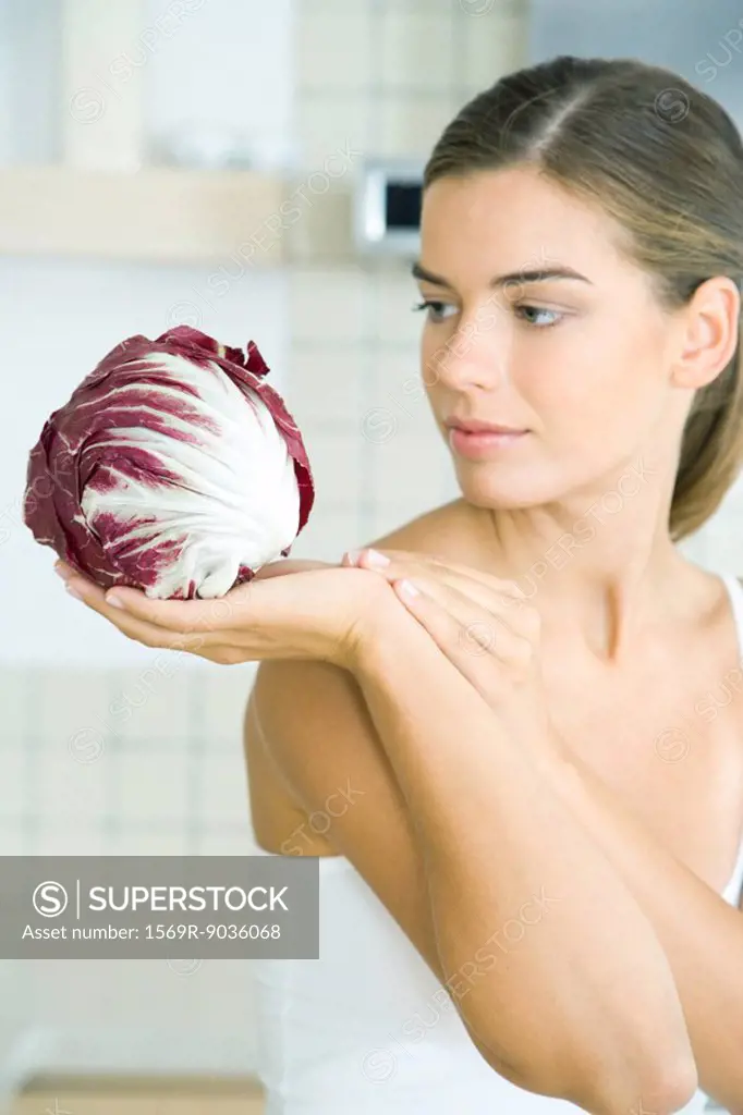 Woman looking at and holding a head of radicchio lettuce