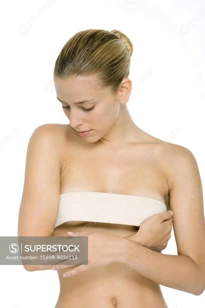 Woman holding bandage across breasts, looking down