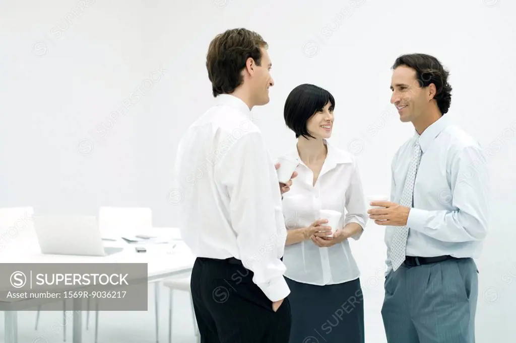 Professionals chatting, holding coffee cups, smiling