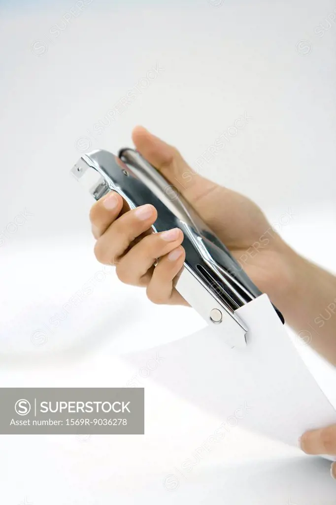 Person using stapler, cropped view of hands