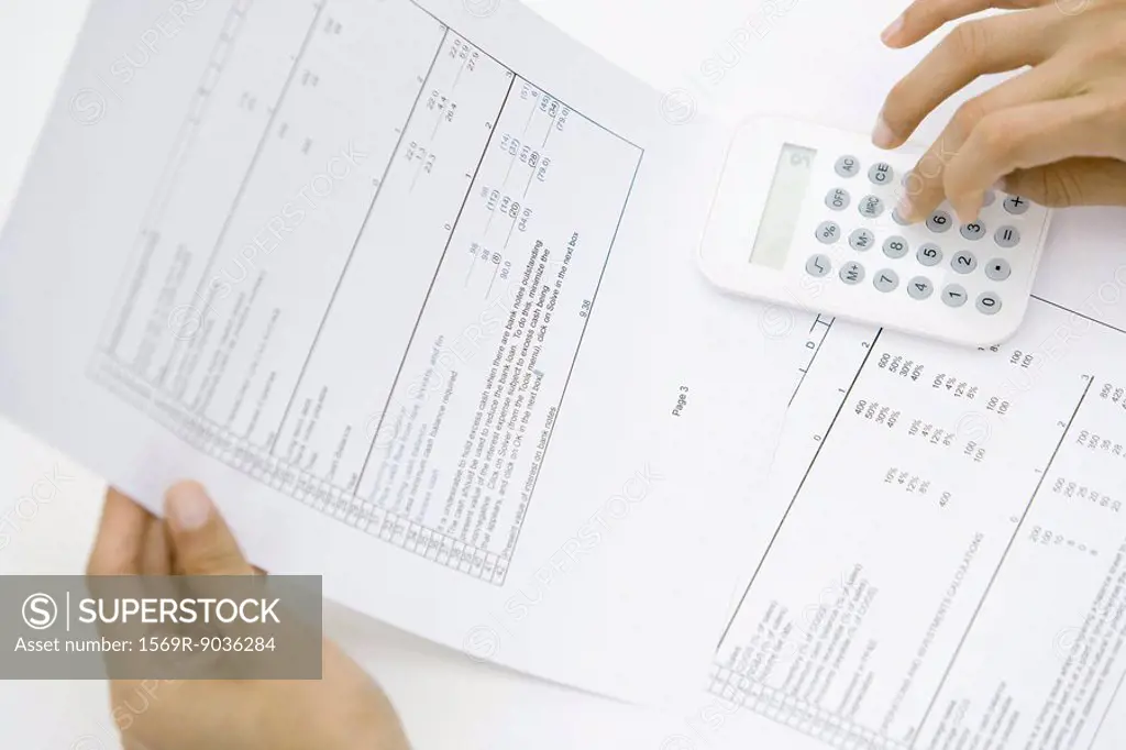 Person holding document, using calculator, cropped view of hands