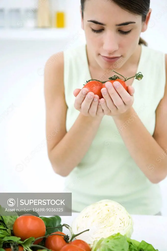 Woman smelling ripe vine tomatoes, close-up