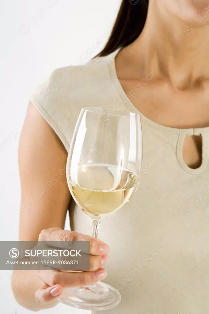 Woman holding glass of white wine, cropped view