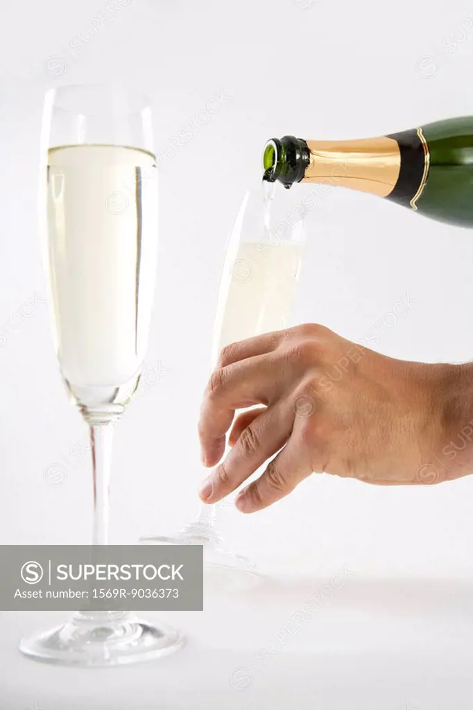 Hand pouring champagne into glasses, close-up