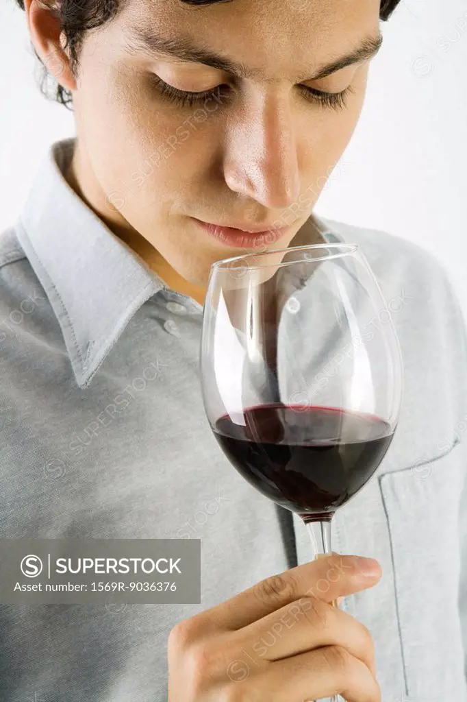 Man examining glass of red wine, close-up