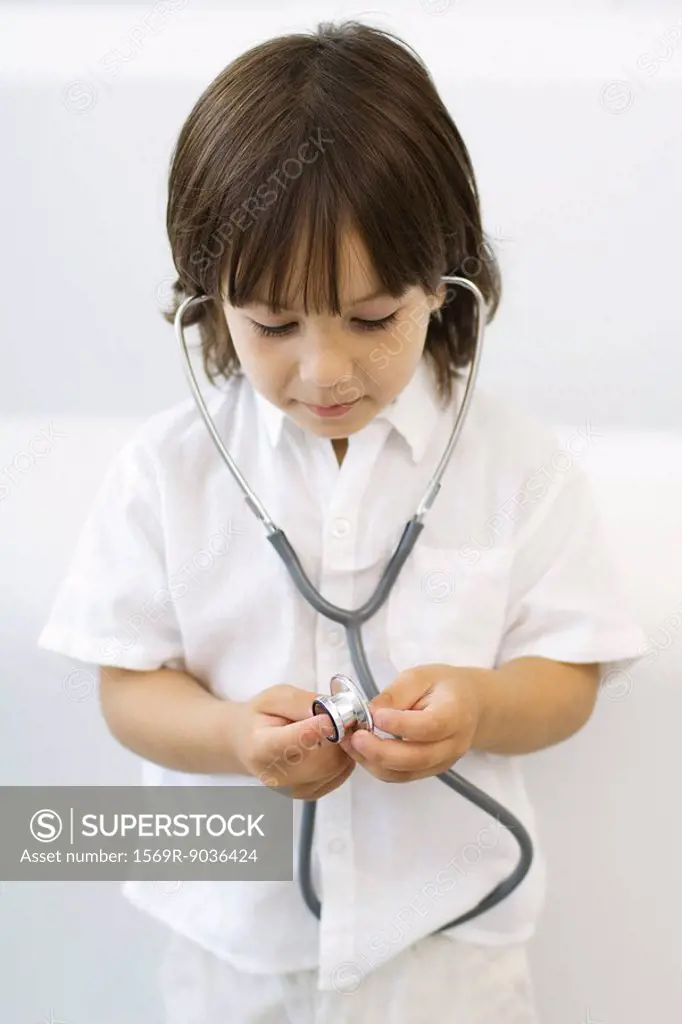 Little boy playing with stethoscope, looking down