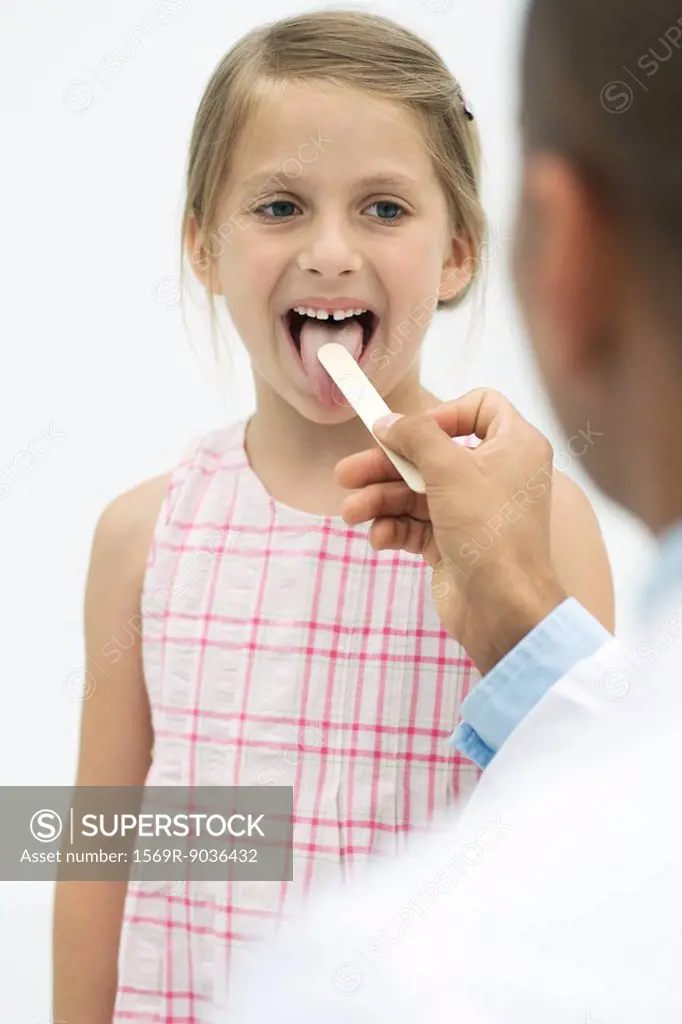Doctor examining a girl´s throat using a tongue depressor