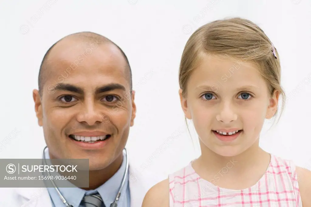 Male doctor beside girl, both smiling at camera, portrait