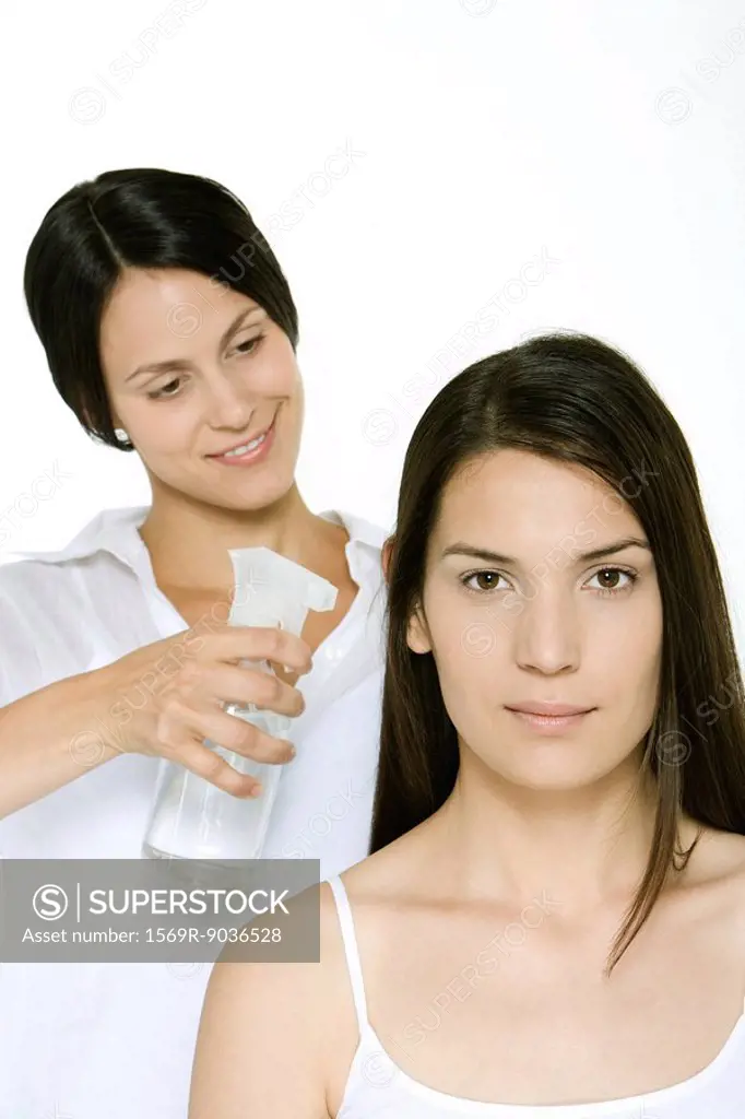 Hair stylist using spray bottle to moisten a woman´s hair