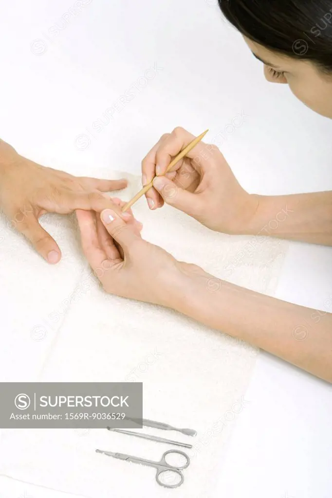 Woman using a cuticle pusher to give a manicure