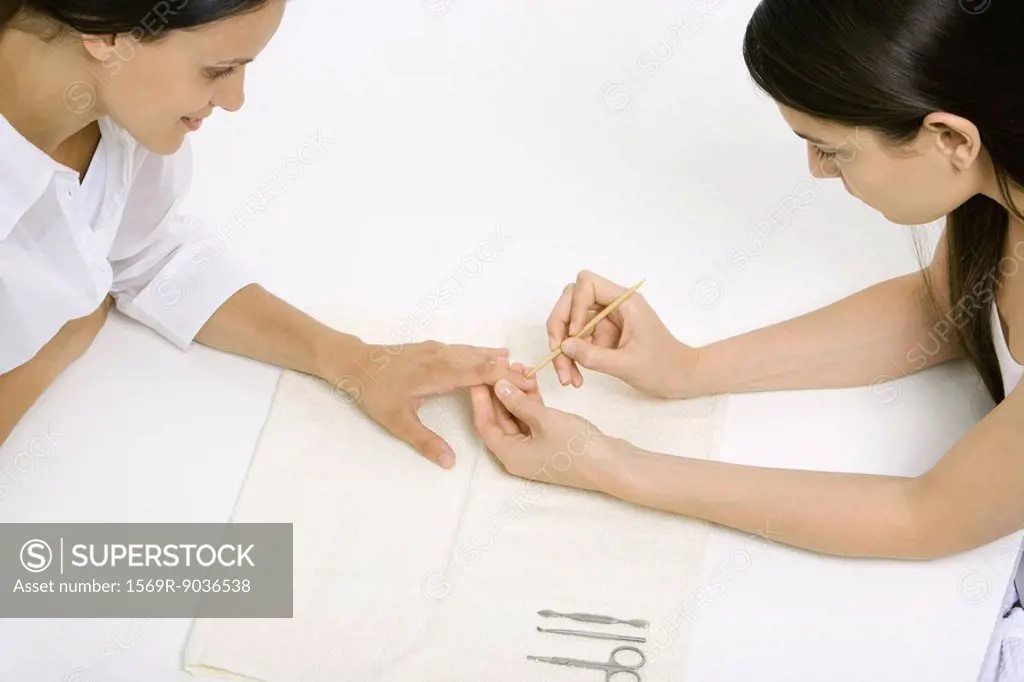 Woman receiving manicure, looking down at hand, cropped view