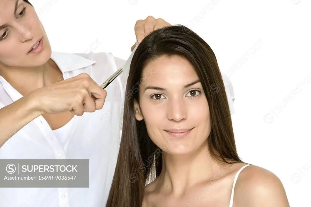Woman having her hair cut by stylist, smiling at camera