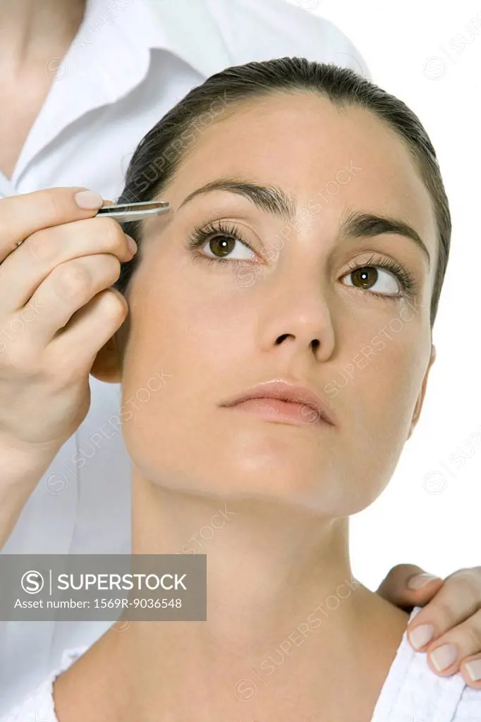 Woman having her eyebrows tweezed, looking up