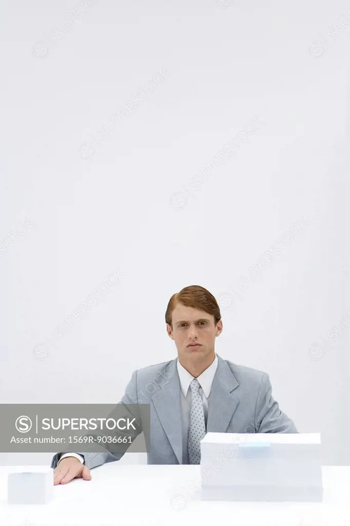 Businessman sitting at table with two different sized stacks of paper