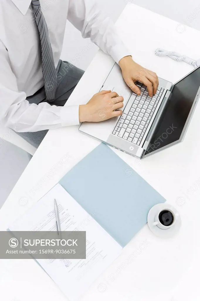 Man using laptop on desk, high angle cropped view
