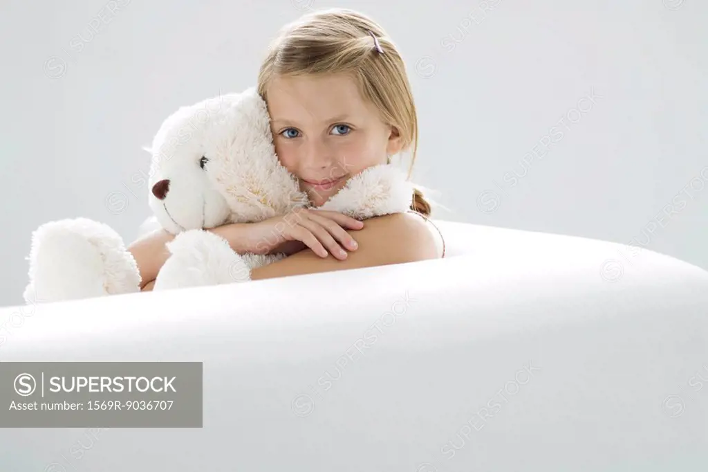 Girl holding teddy bear, smiling at camera