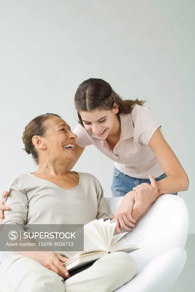 Grandmother holding book, granddaughter looking over her shoulder