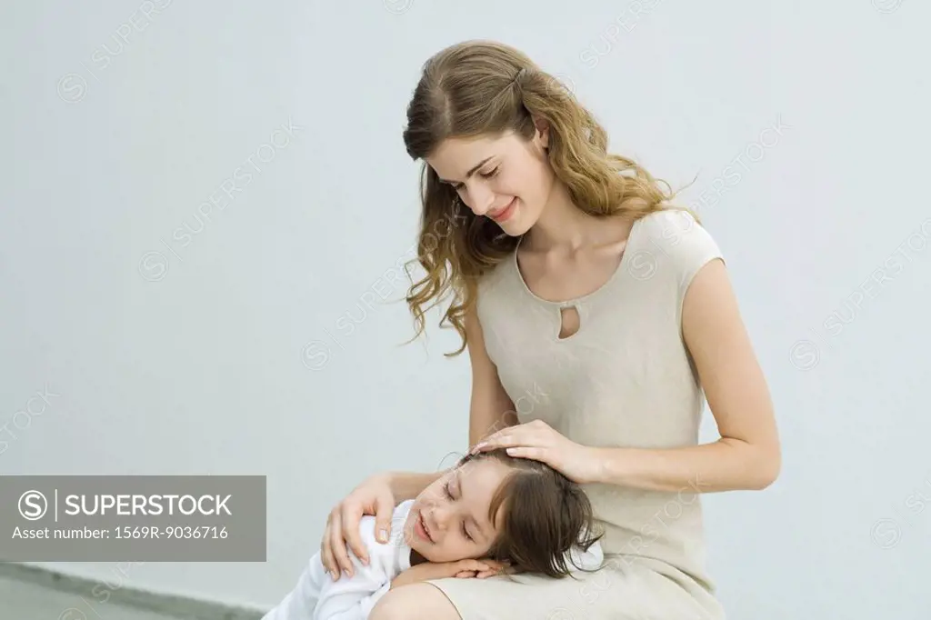 Little boy resting head on mother´s lap, woman stroking child´s hair