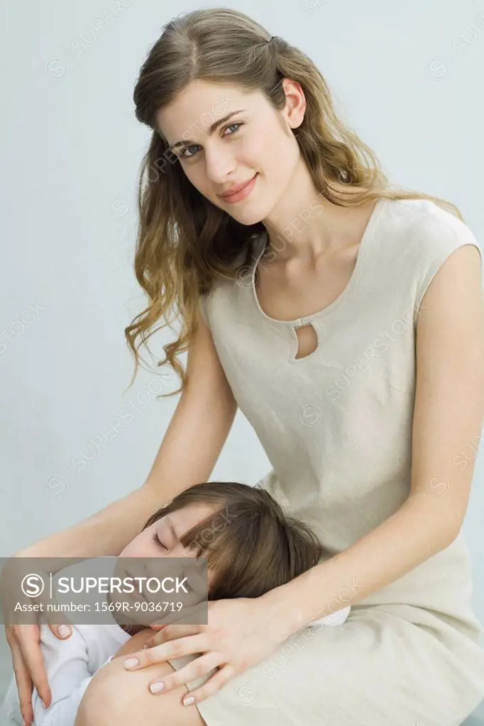 Little boy resting head on mother´s lap, woman smiling at camera
