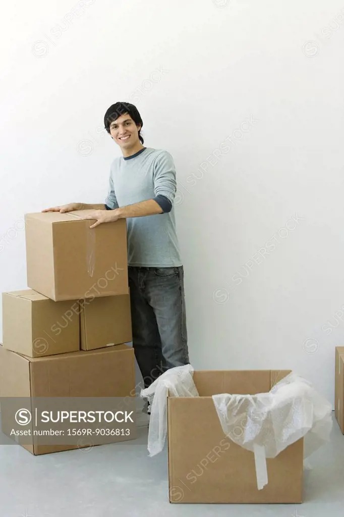 Man standing by stack of cardboard boxes, smiling at camera