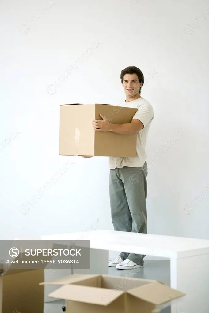 Man holding cardboard box, smiling at camera, opened boxes in foreground