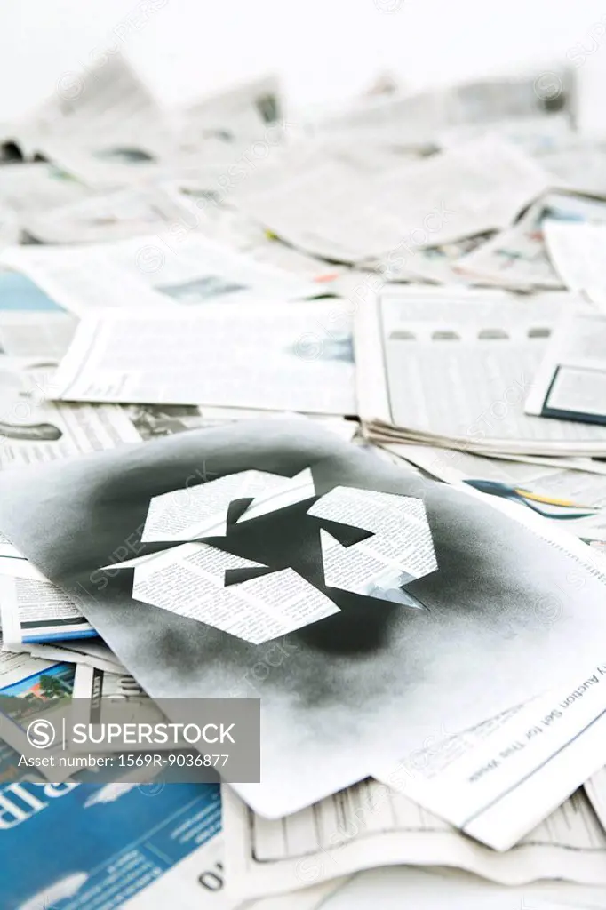Recycling symbol stenciled on pile of newspapers
