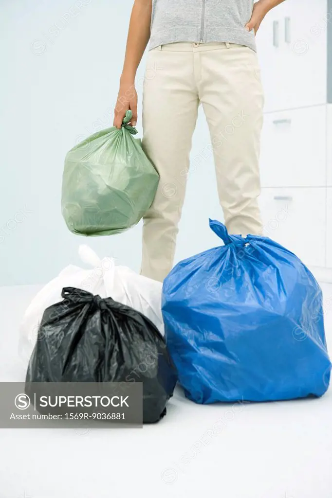 Teen girl with several bags of garbage, cropped view
