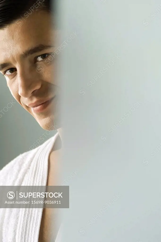 Man in bathrobe smiling at camera, cropped view