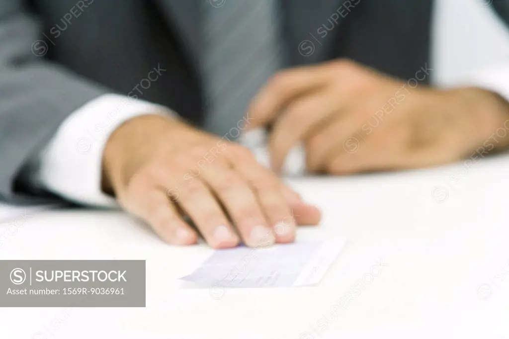 Businessman holding check, low angle view, cropped