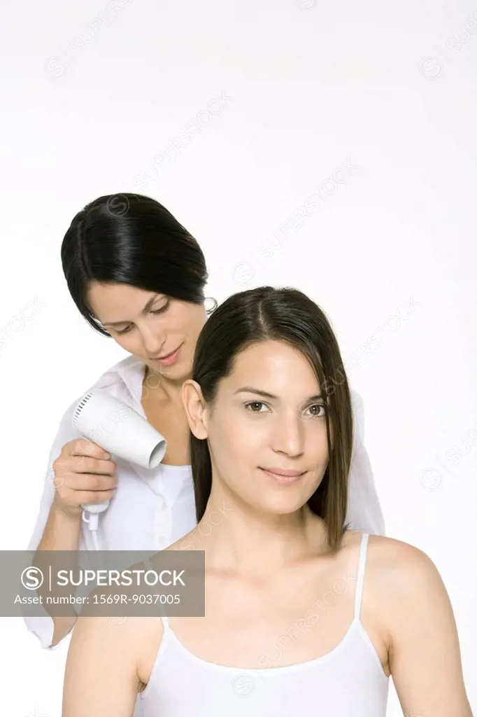 Woman having hair dried by stylist, smiling at camera
