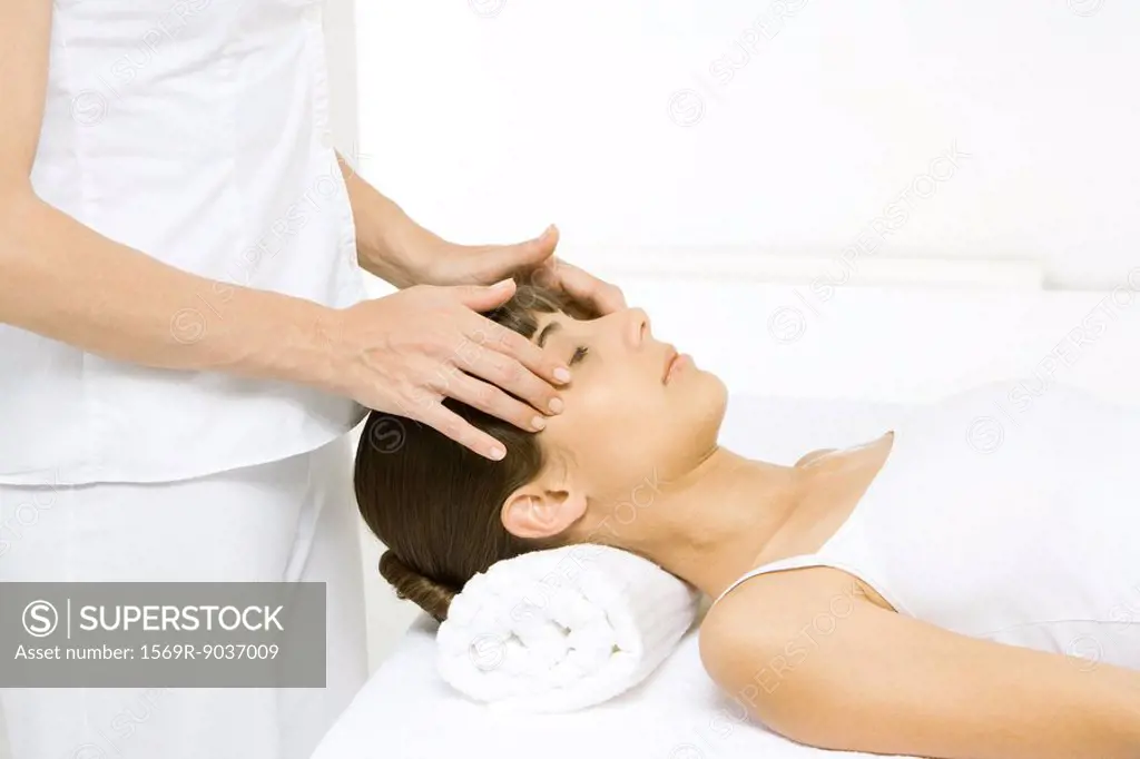 Woman lying down, receiving head massage, side view