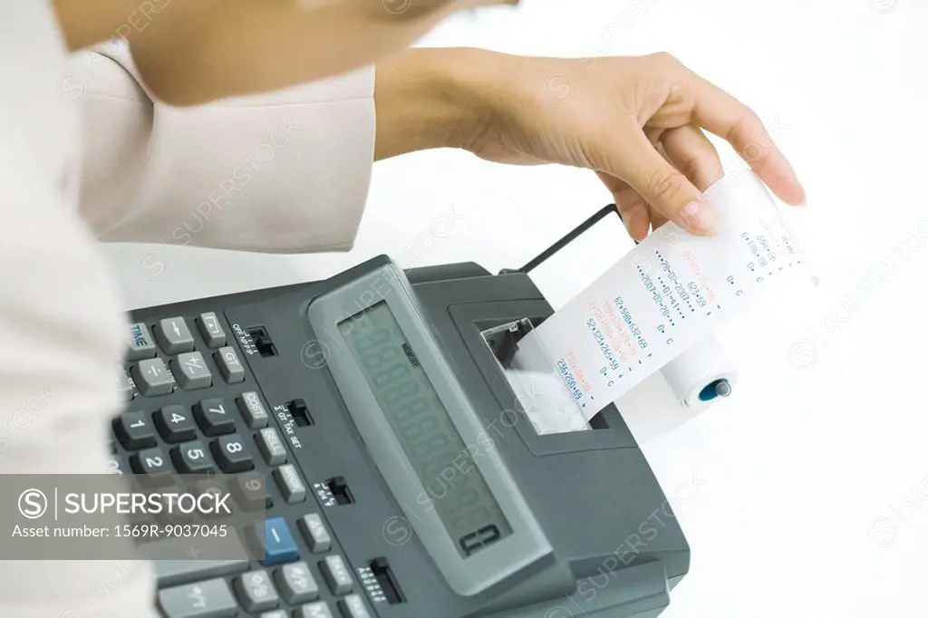 Businesswoman using adding machine, holding printout, cropped view