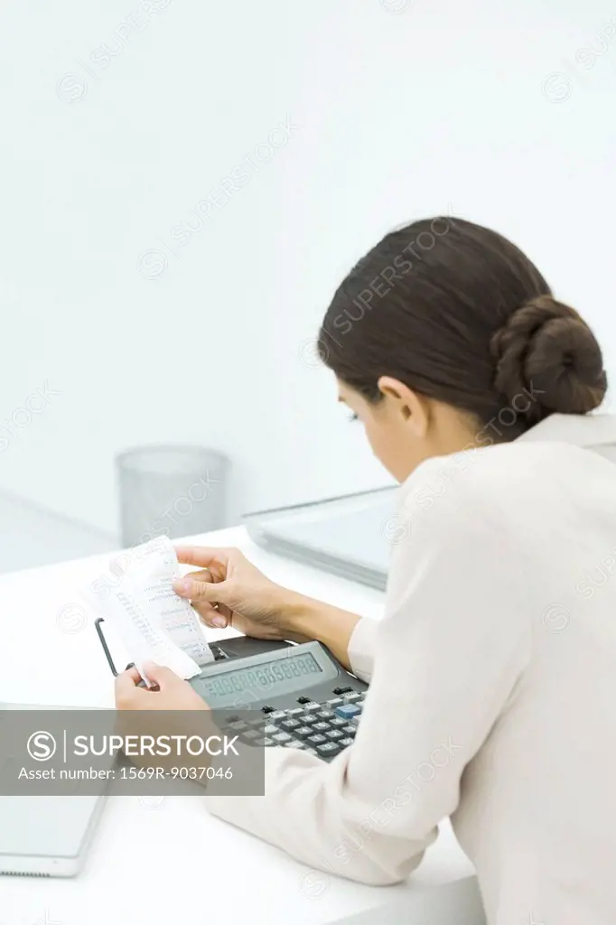 Businesswoman using adding machine, holding receipt, rear view