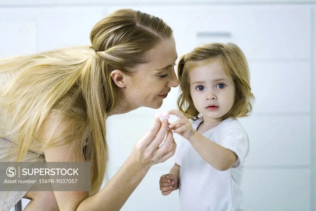 Little girl giving her mother a tiny heart, looking at camera